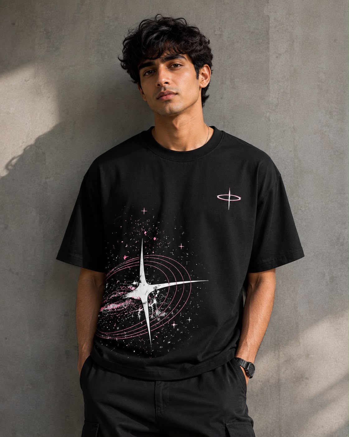 Cosmic Black — model in the Oversized Graphic T-Shirt with the pink and white starburst print, against a concrete wall