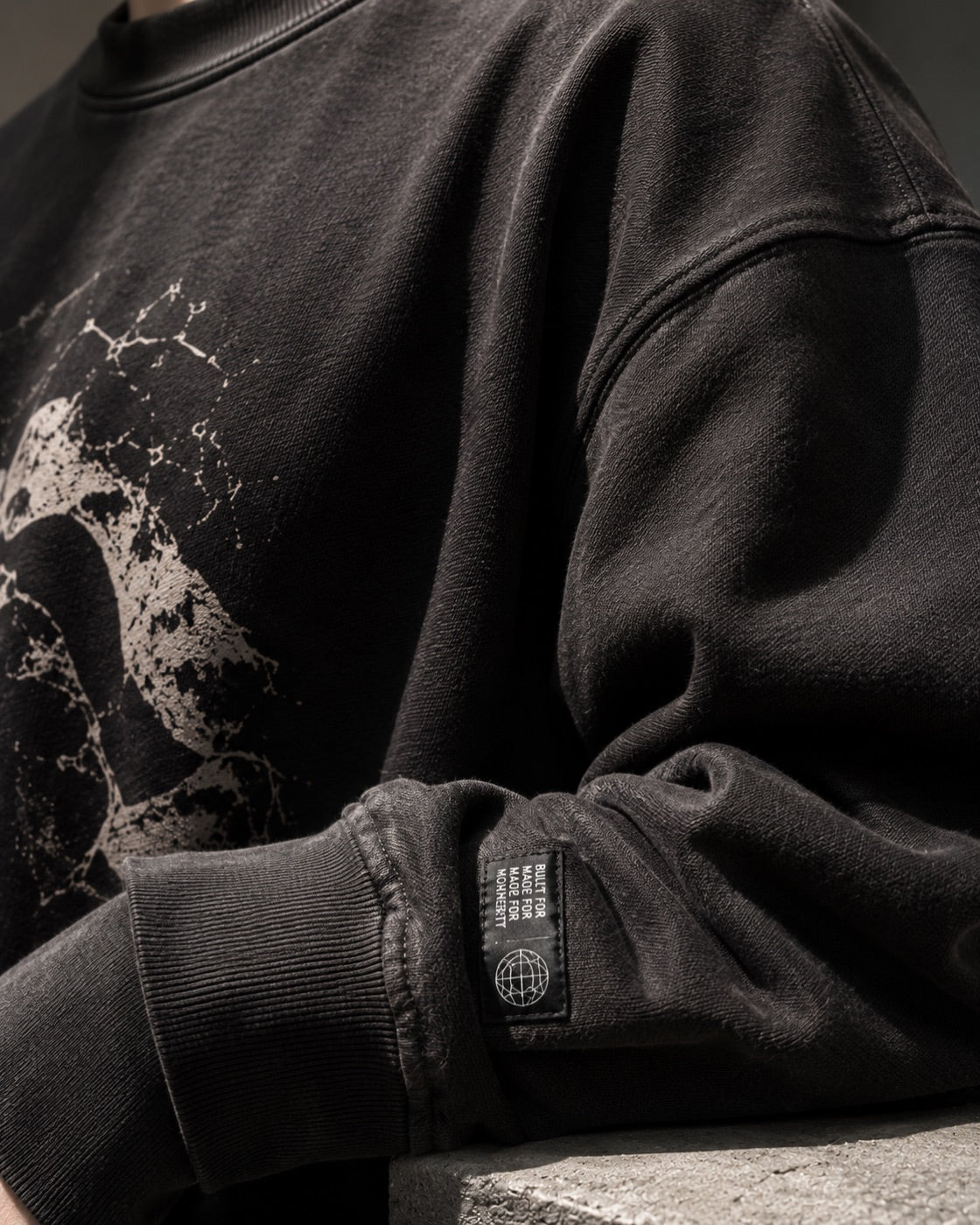 Close detail of a washed black Seoul & Saint sweatshirt cuff and woven label